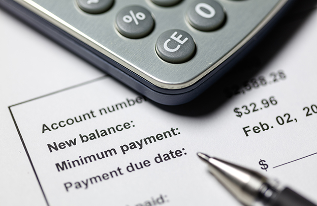 Calculator and pen on top of credit card bill statement