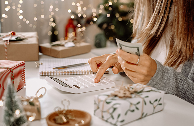 Woman doing budget with calculator for holiday shopping.